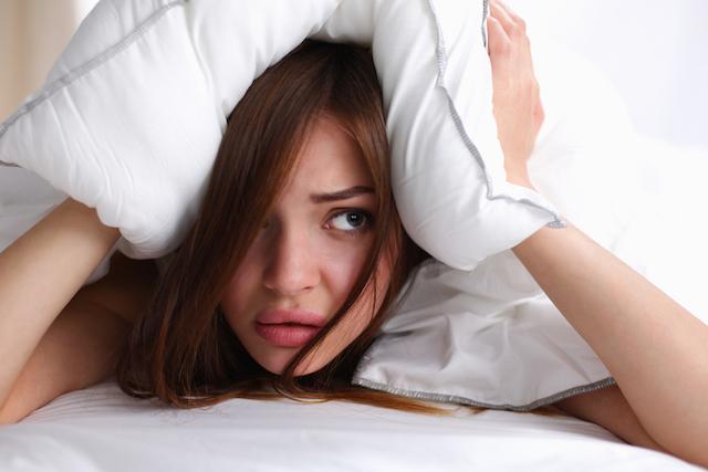 Женщина прячется под подушкой